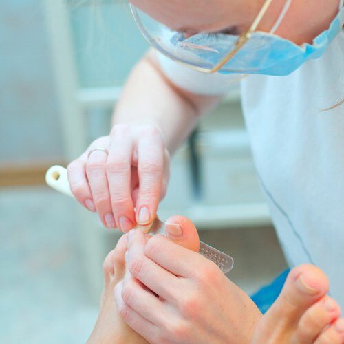 A podiatrist treating a patient's toe